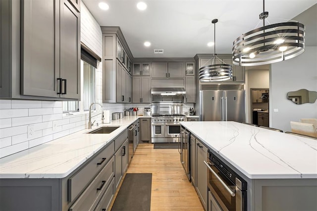 kitchen featuring sink, pendant lighting, high quality appliances, light hardwood / wood-style floors, and a kitchen island