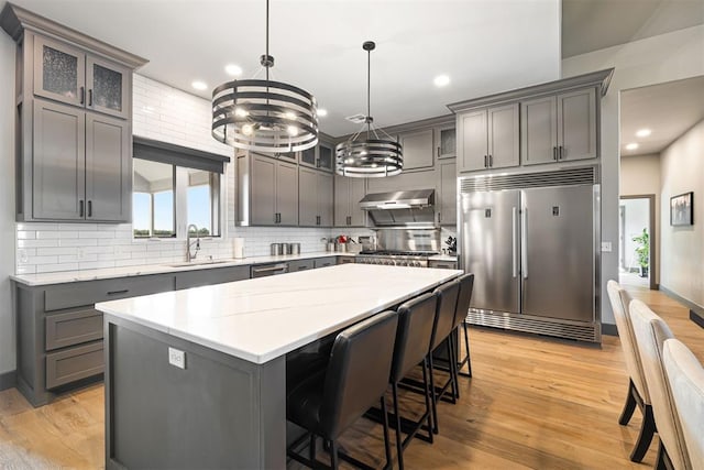 kitchen with a center island, sink, stainless steel appliances, pendant lighting, and extractor fan