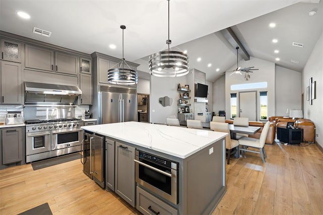 kitchen with pendant lighting, premium appliances, ceiling fan with notable chandelier, and light hardwood / wood-style flooring