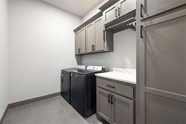 laundry room with cabinets, light tile patterned floors, and washer and dryer