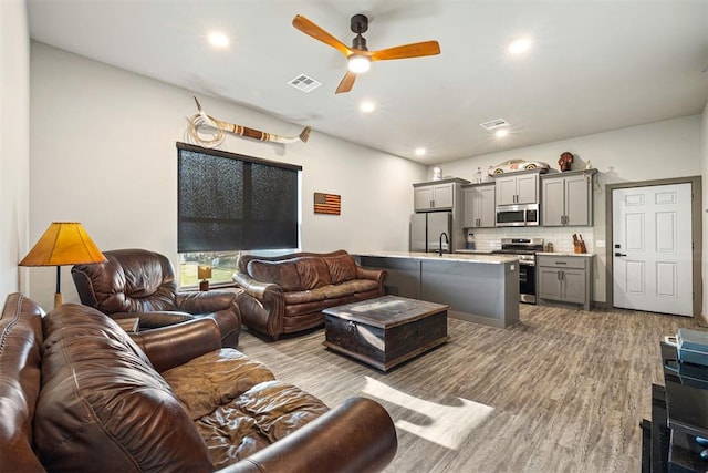 living room with light hardwood / wood-style flooring, ceiling fan, and sink