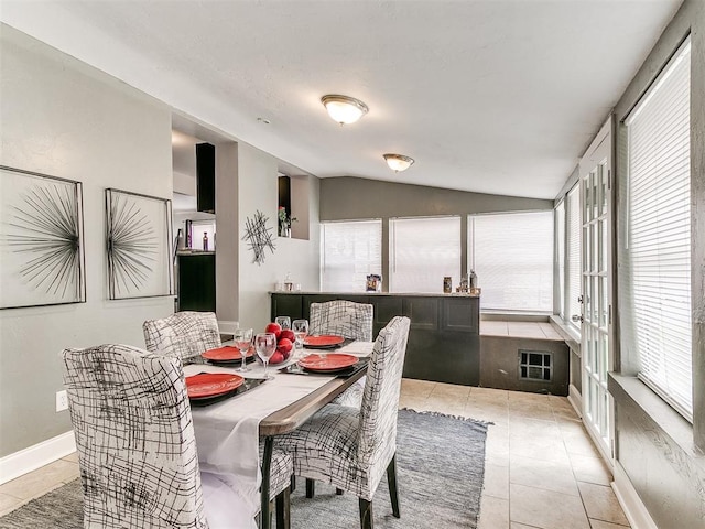 tiled dining room with lofted ceiling