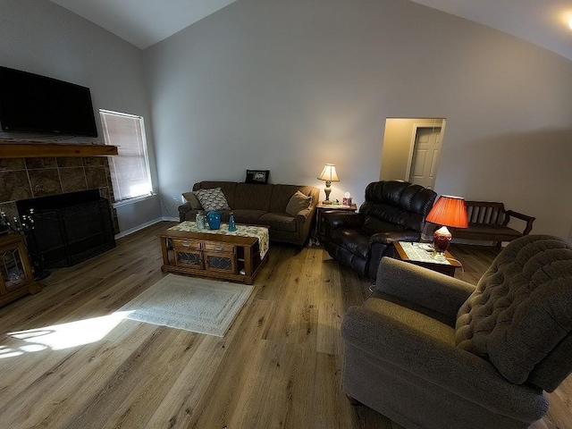 living room with a fireplace, high vaulted ceiling, and wood-type flooring