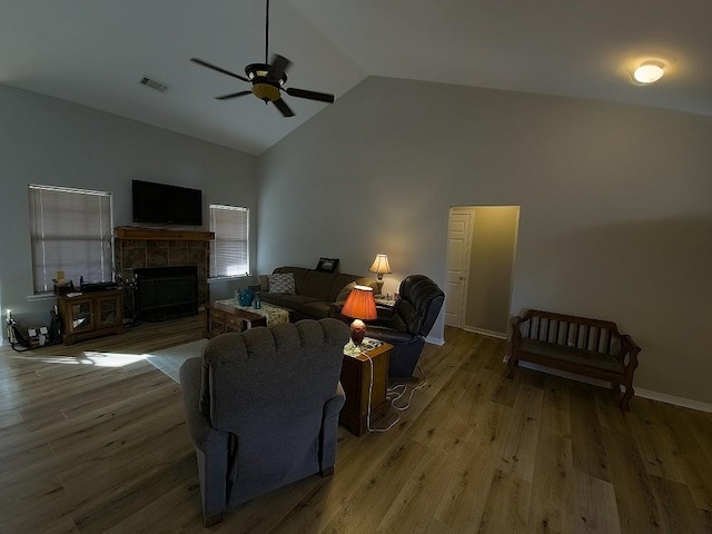 living room featuring a tile fireplace, hardwood / wood-style floors, high vaulted ceiling, and ceiling fan