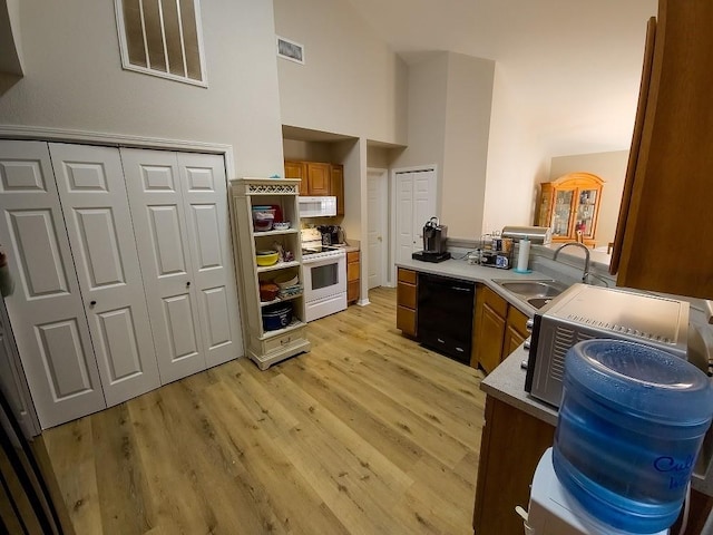 kitchen with sink, high vaulted ceiling, light hardwood / wood-style floors, and white appliances