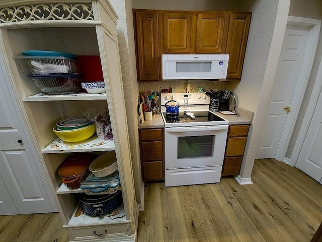 kitchen with white appliances and light hardwood / wood-style flooring