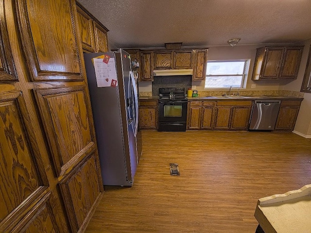 kitchen featuring sink, stainless steel appliances, a textured ceiling, and light wood-type flooring