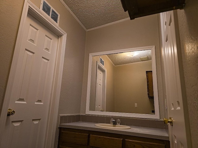 bathroom with a textured ceiling, vanity, and crown molding