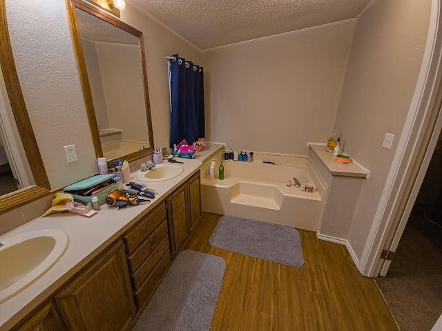 bathroom with a bath, crown molding, hardwood / wood-style floors, a textured ceiling, and vanity