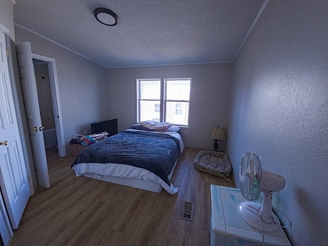 bedroom featuring a textured ceiling, wood-type flooring, and ornamental molding