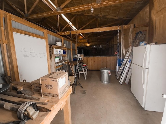 interior space featuring vaulted ceiling, wooden walls, and concrete floors