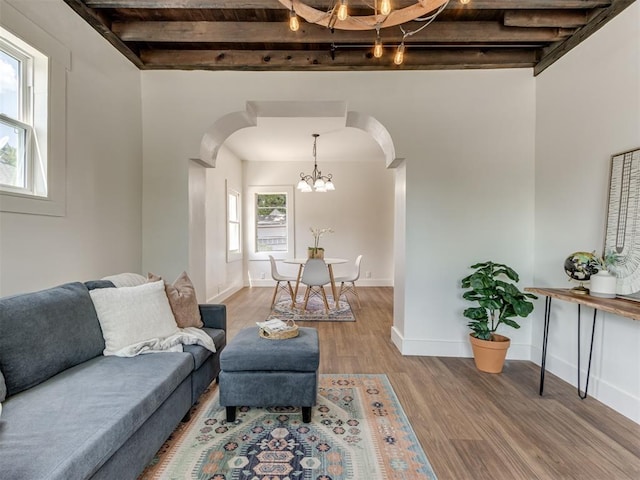 living room featuring hardwood / wood-style flooring, beam ceiling, and an inviting chandelier