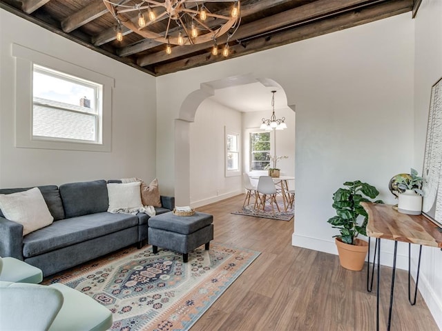 living room featuring hardwood / wood-style flooring, a notable chandelier, wood ceiling, and beamed ceiling