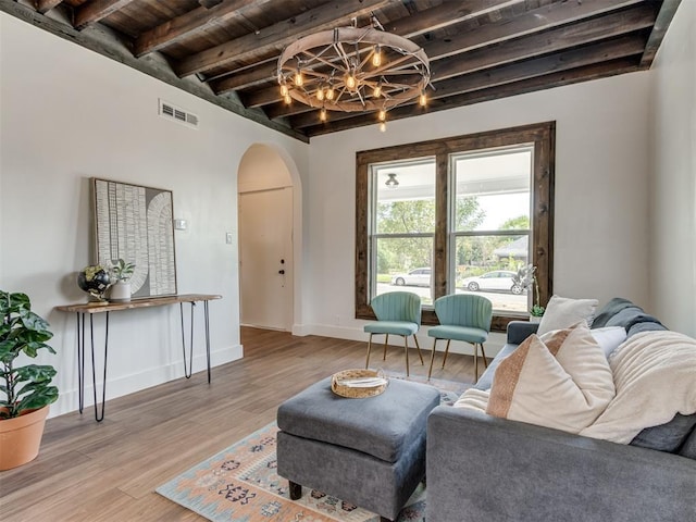 living room featuring beamed ceiling, a notable chandelier, wooden ceiling, and light hardwood / wood-style floors