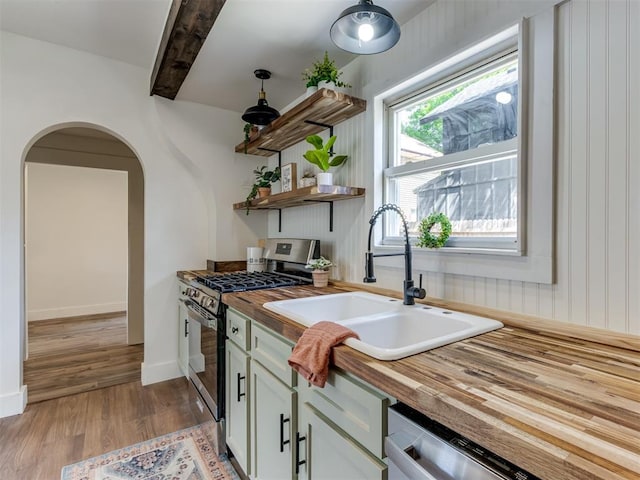 kitchen featuring sink, light hardwood / wood-style flooring, appliances with stainless steel finishes, butcher block counters, and beam ceiling