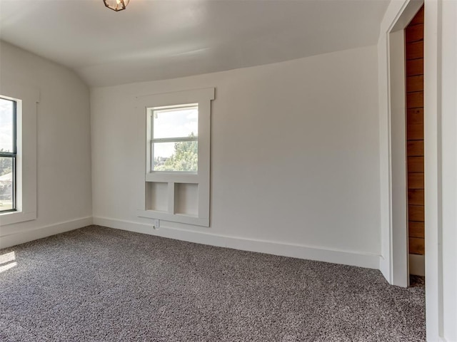 carpeted empty room featuring vaulted ceiling