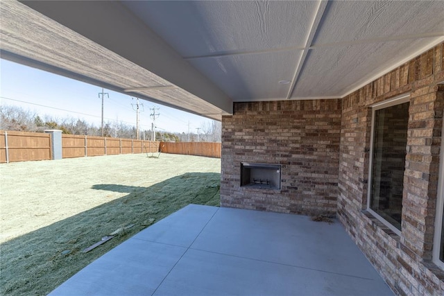 view of patio with an outdoor brick fireplace and fence