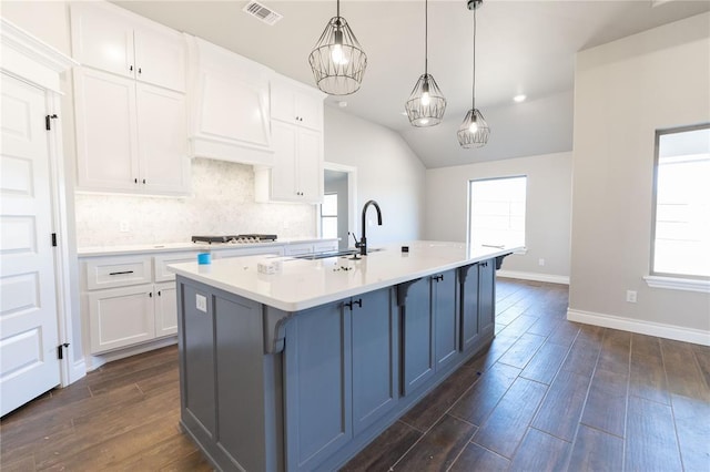 kitchen with light countertops, a sink, a wealth of natural light, and custom range hood