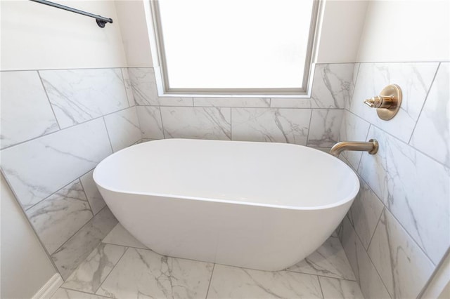 bathroom featuring a soaking tub and marble finish floor