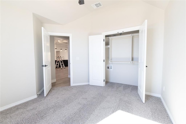 unfurnished bedroom with carpet, a closet, visible vents, vaulted ceiling, and baseboards