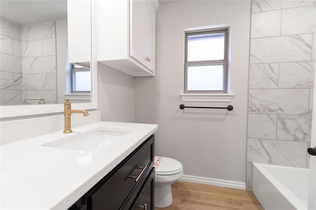 full bath featuring toilet, wood finished floors, vanity, baseboards, and a wealth of natural light