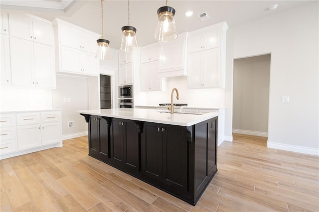 kitchen with light countertops, dark cabinets, light wood-style flooring, and white cabinets