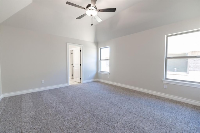 empty room featuring lofted ceiling, ceiling fan, baseboards, and light colored carpet