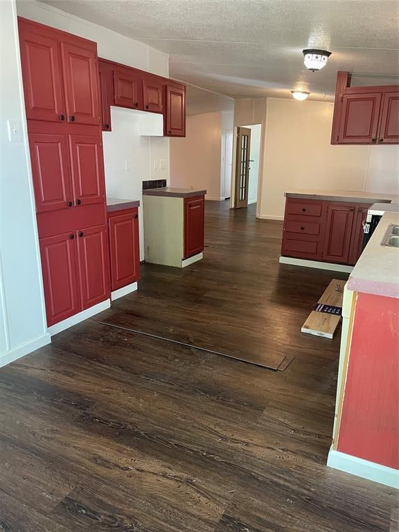 kitchen with a textured ceiling and dark wood-type flooring