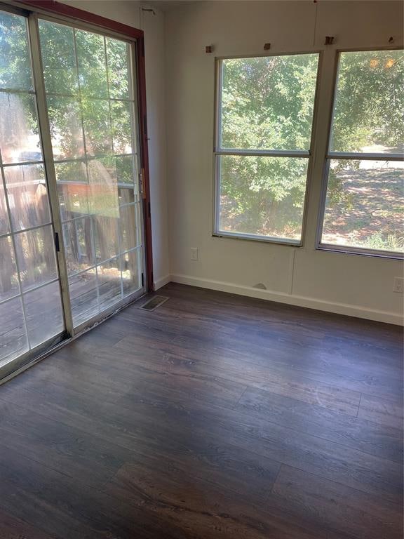 unfurnished room with dark wood-type flooring and a healthy amount of sunlight