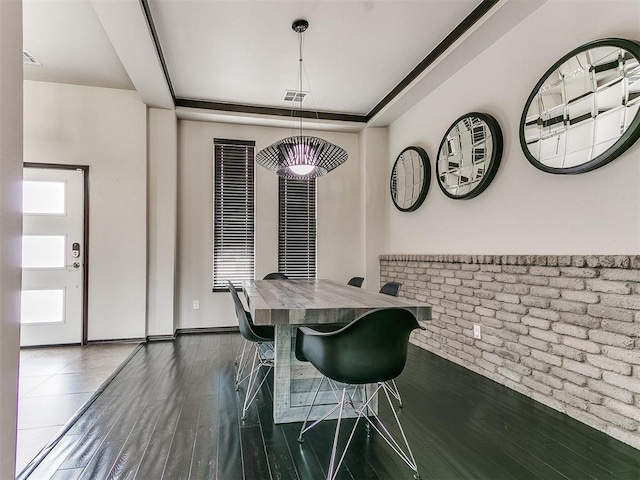 dining area featuring dark hardwood / wood-style flooring and brick wall