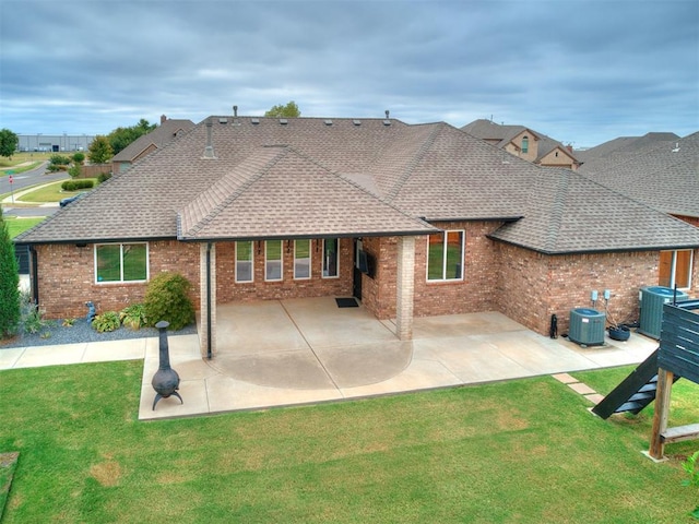 back of property with central AC unit, a patio area, and a lawn