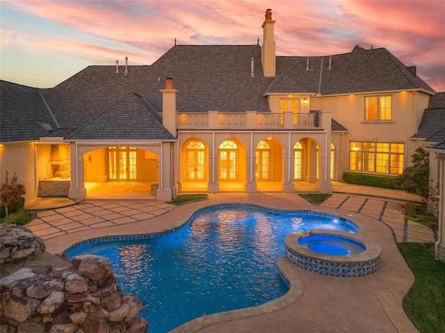 pool at dusk with an in ground hot tub, french doors, and a patio