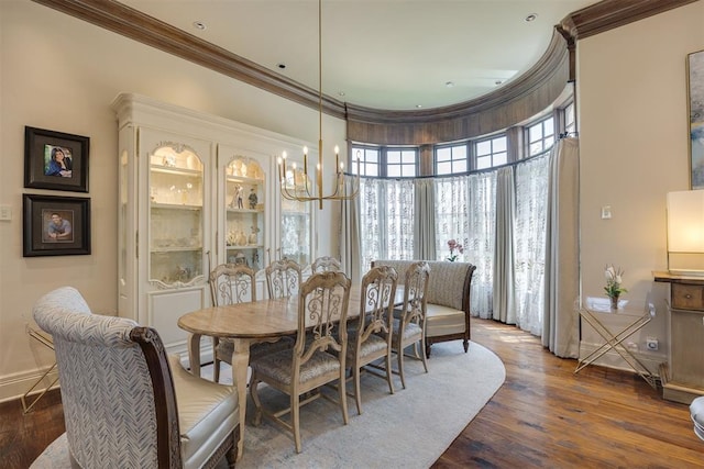 dining area featuring a high ceiling, dark wood-type flooring, a notable chandelier, and ornamental molding