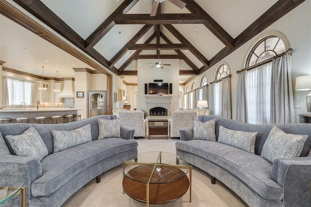 living room with beam ceiling, high vaulted ceiling, ceiling fan, and sink