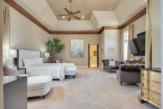 bedroom with light colored carpet, a tray ceiling, ceiling fan, crown molding, and connected bathroom