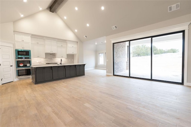 kitchen featuring white cabinetry, backsplash, visible vents, and built in microwave