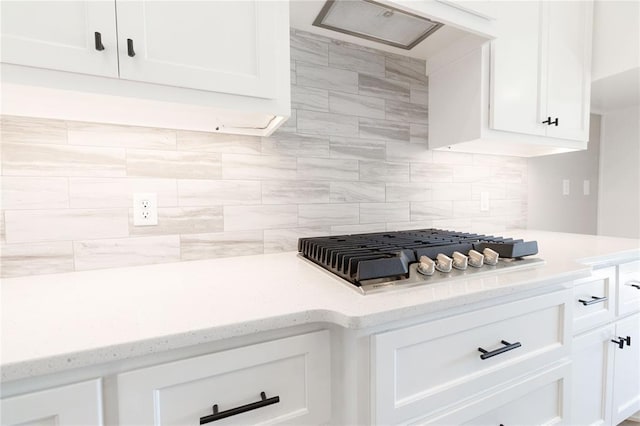 interior details with decorative backsplash, white cabinetry, and stainless steel gas stovetop