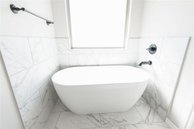 bathroom featuring a freestanding bath and marble finish floor