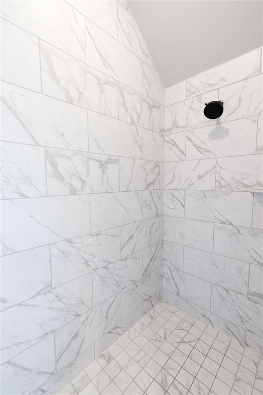 full bath with a tile shower and vaulted ceiling
