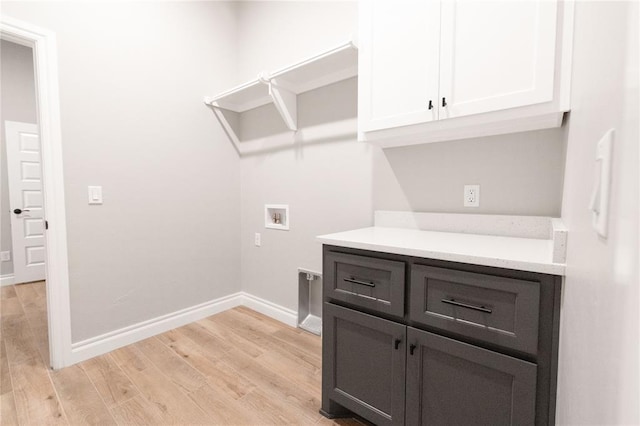 washroom featuring light wood finished floors, washer hookup, baseboards, and cabinet space