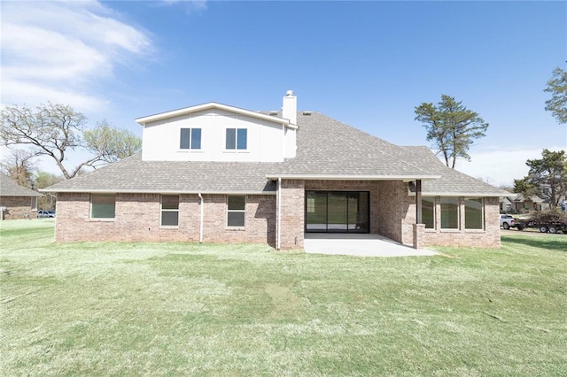 rear view of house featuring a patio area, brick siding, a lawn, and roof with shingles