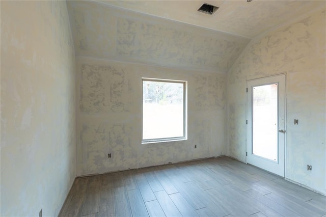 spare room featuring lofted ceiling and light hardwood / wood-style flooring