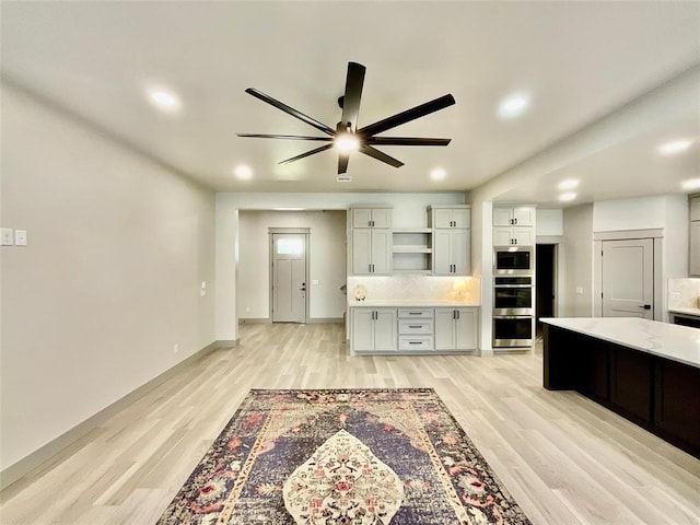 kitchen with appliances with stainless steel finishes, tasteful backsplash, light hardwood / wood-style flooring, and ceiling fan