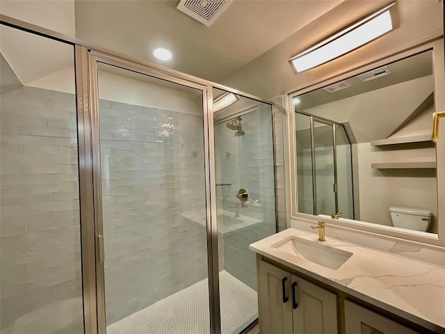 bathroom featuring vanity, toilet, and a shower with shower door