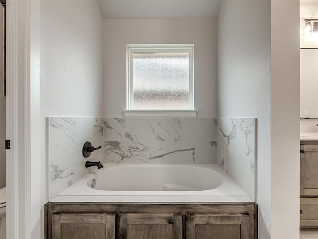 bathroom with a tub to relax in and toilet