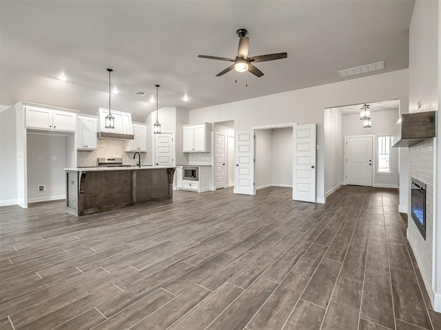 kitchen with white cabinetry, an island with sink, tasteful backsplash, and decorative light fixtures