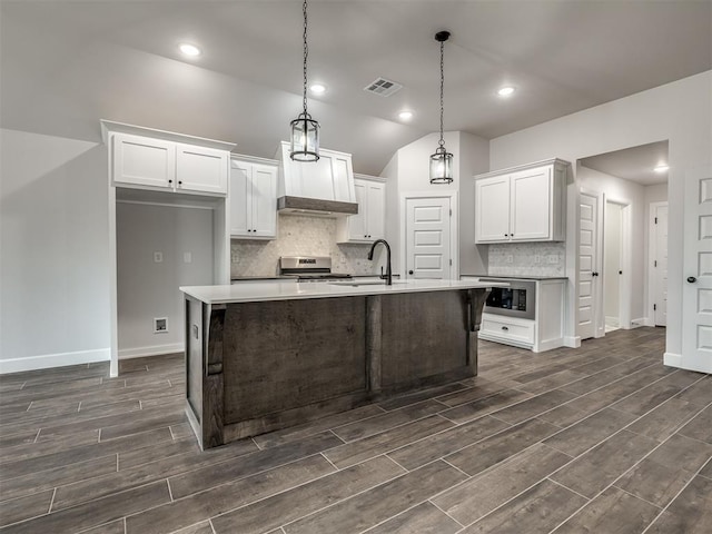 kitchen featuring hanging light fixtures, white cabinetry, a center island with sink, and electric range