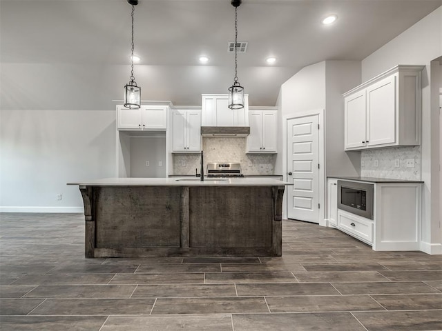 kitchen featuring white cabinetry, appliances with stainless steel finishes, a kitchen island with sink, and hanging light fixtures