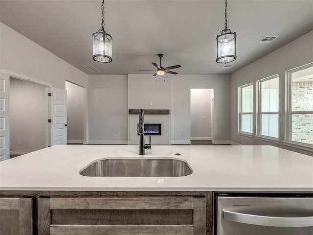 kitchen with pendant lighting, sink, an island with sink, and dishwasher