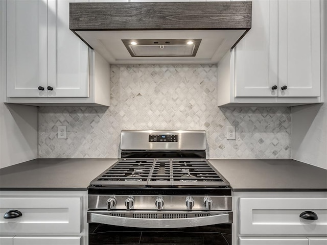 kitchen with custom range hood, stainless steel range with gas stovetop, white cabinets, and decorative backsplash